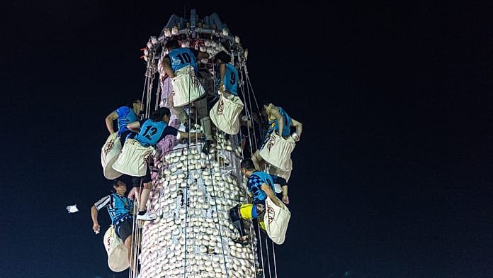 Unos escaladores compiten en una torre de bollos del colorido festival de Hong Kong
